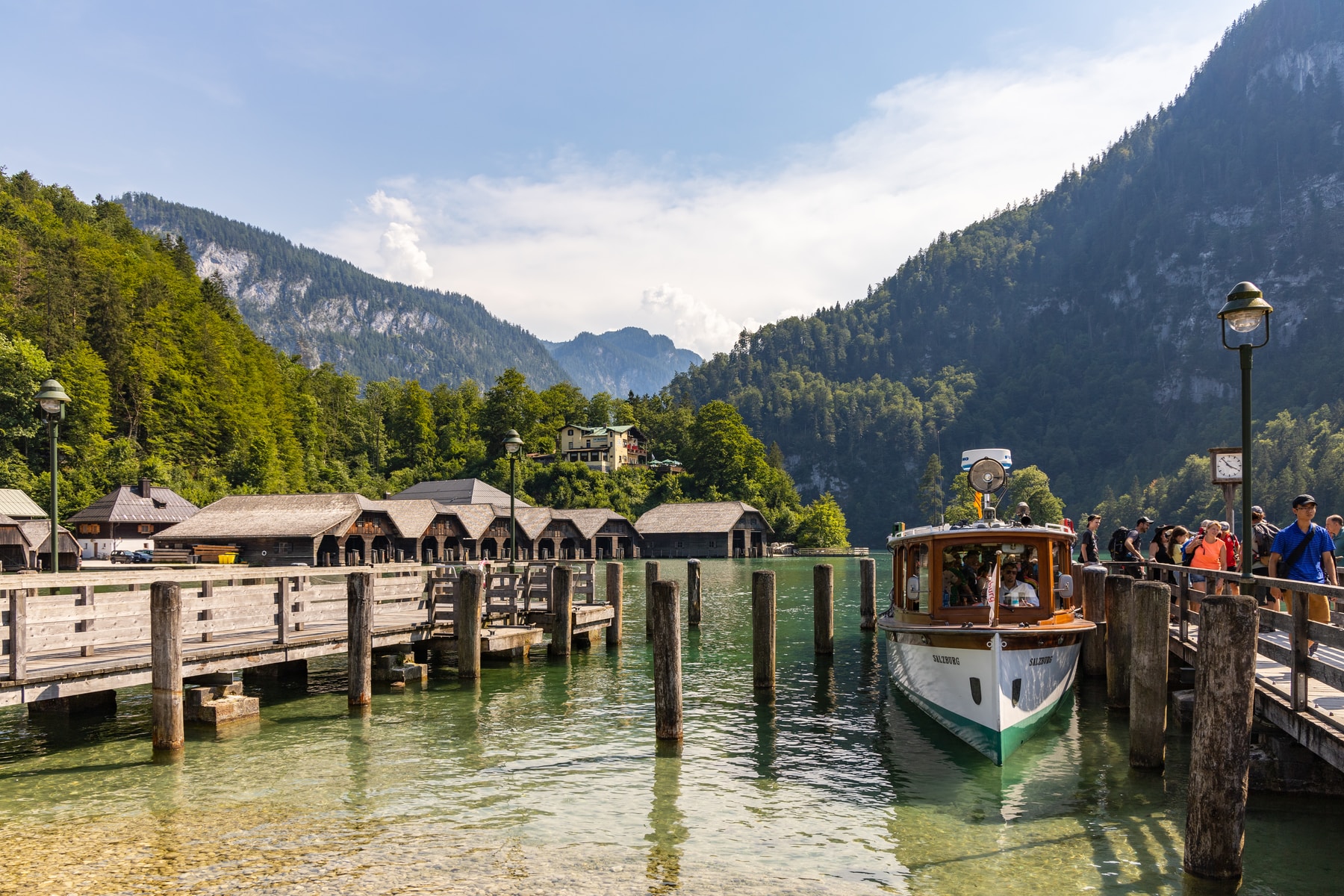 white and brown boat on water near green trees and mountain during daytime