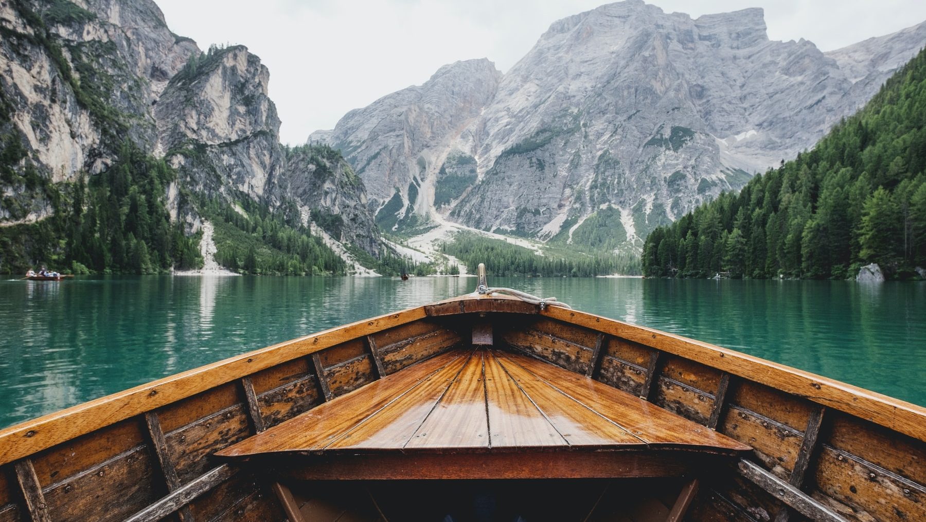 brown wooden boat moving towards the mountain